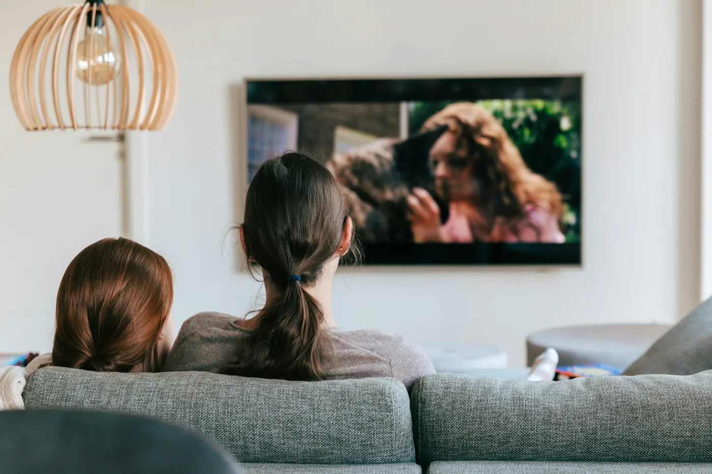 A mother and child watching television together on a sofa